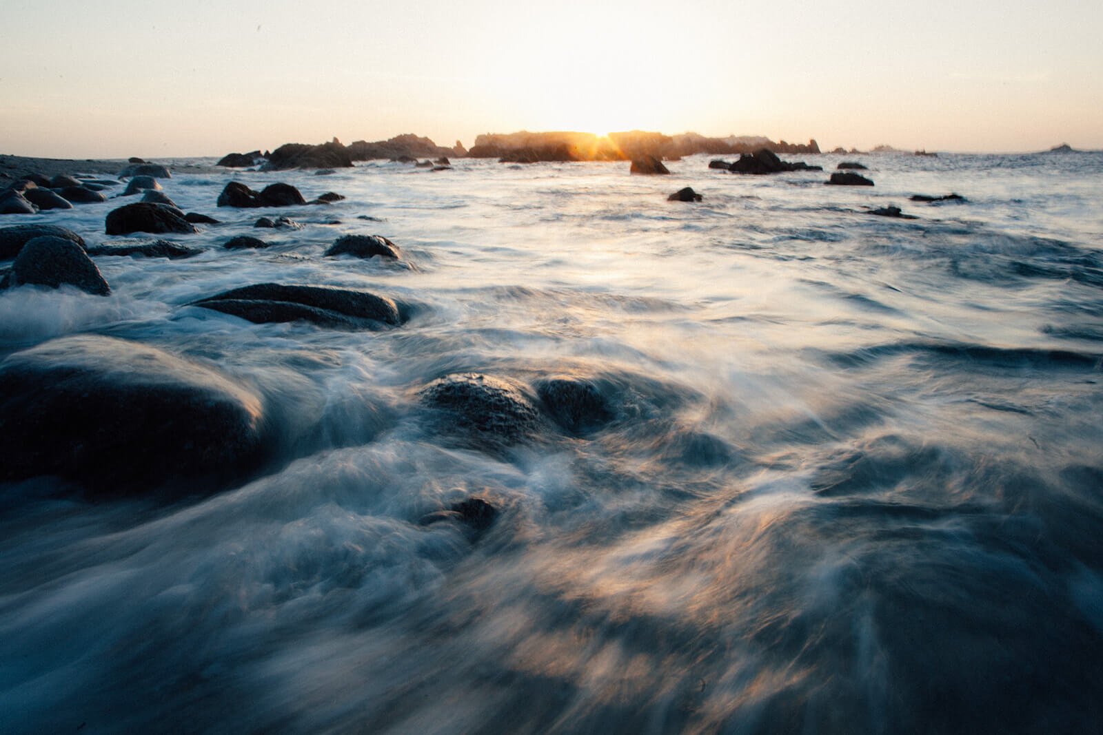 Ocean rushing over rocks at sunset